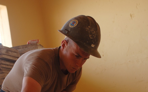 Petty Officer 3rd Class Patrick Dixon applies mortar to the floor.