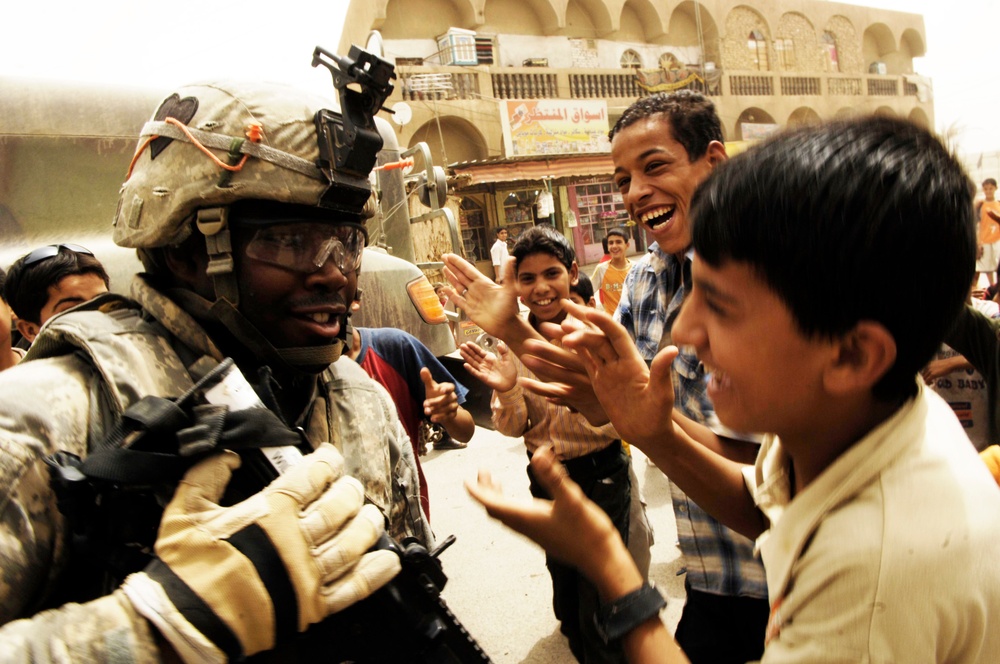 Sgt. David Williams dances while Iraqi children sing and clap.