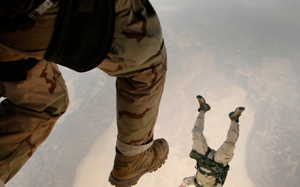 U.S. Air Force pararescuemen leap from a CH-53 Sea Stallion helicopter.