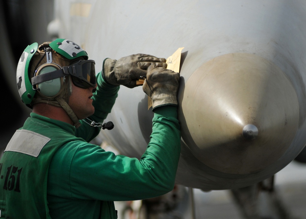 A flight deck chief notes the status of an F/A-18C Hornet aircraft.
