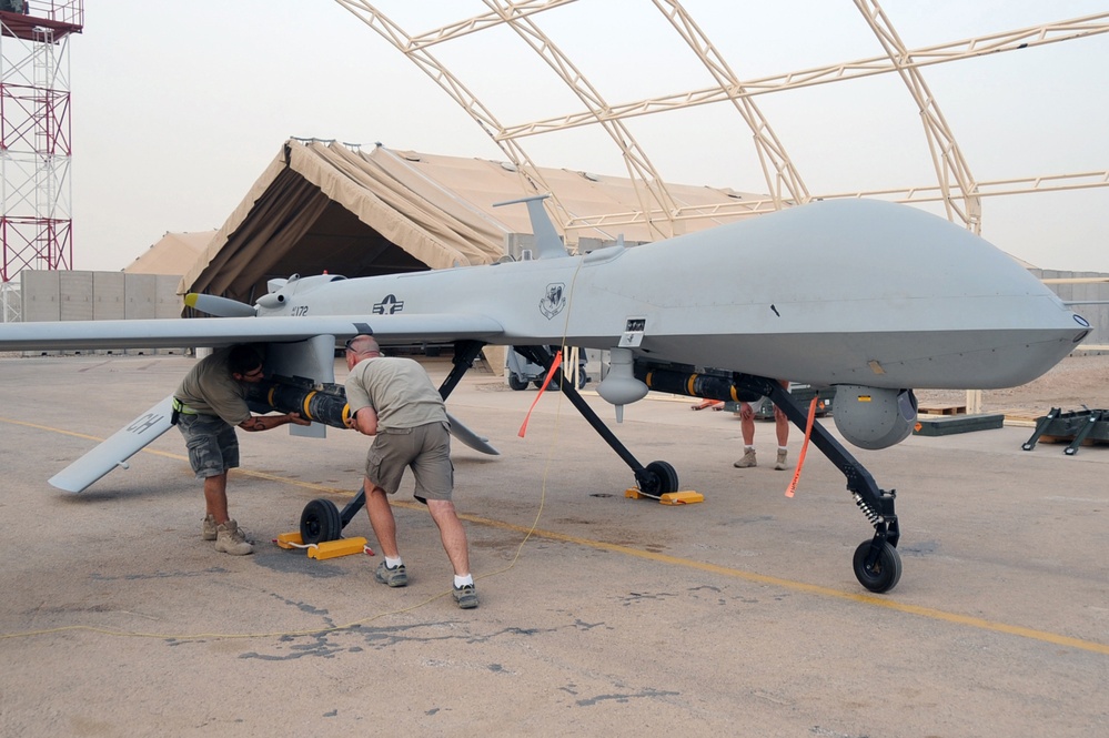 Shilo Thompson and Brandon Walker load an AFM-114 Hellfire missile onto an MQ-1B Predator.