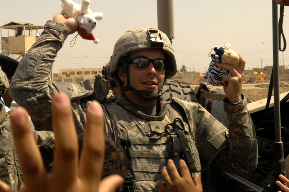 Cpl. Michael McNally hands out stuffed animals to Iraqi children.