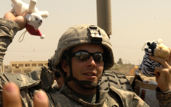 Cpl. Michael McNally hands out stuffed animals to Iraqi children.