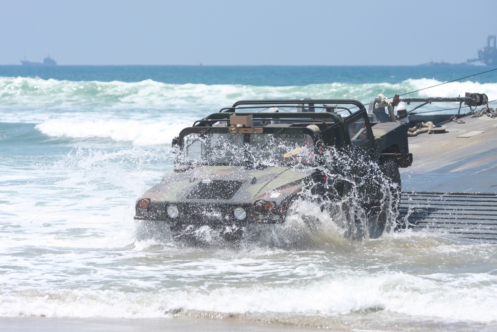 U.S. Army soldiers offload a Humvee from a floating causeway.