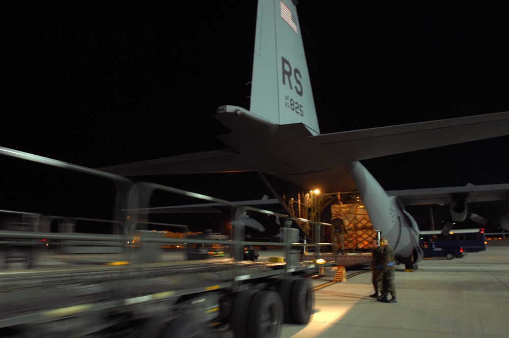 U.S. Air Force airmen load cargo onto a C-130 Hercules aircraft.