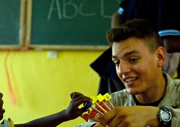 Lance Cpl. Kyle Tucker gives a pencil to a young boy.