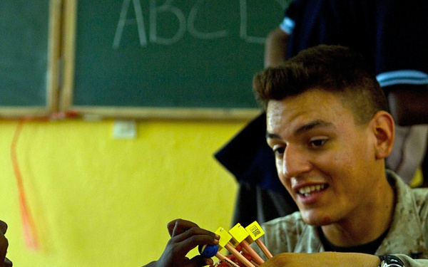 Lance Cpl. Kyle Tucker gives a pencil to a young boy.