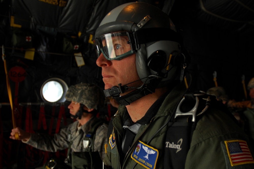 A U.S. Air Force pararescueman looks out the back of a C-130 Hercules aircraft.