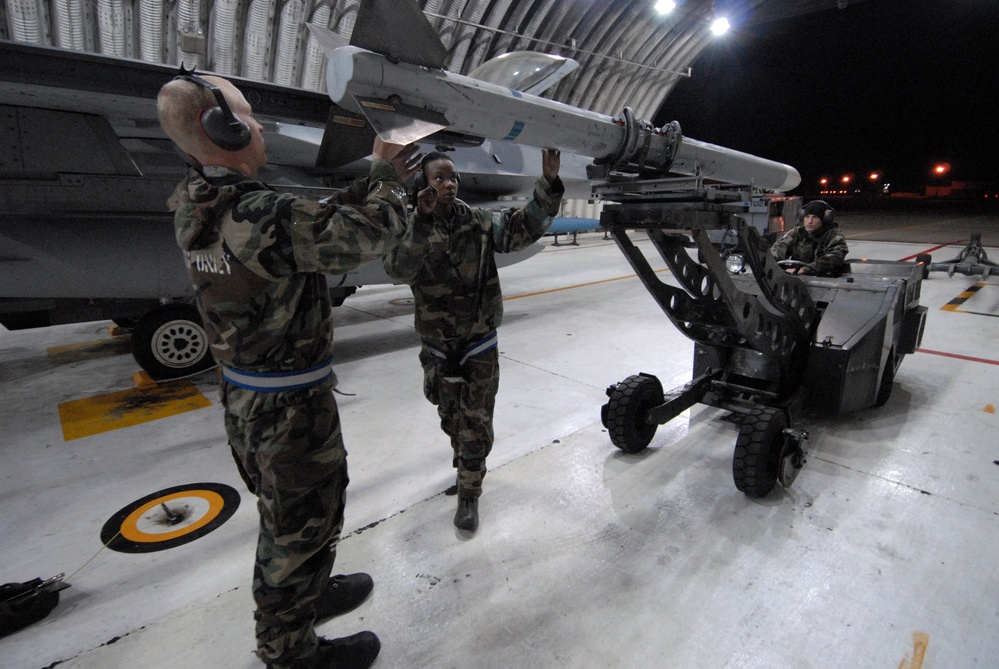 Airman 1st Class Joshua Hnatiuk, Senior Airman Brianne Brown and Airman 1st Class Corey Radel load an AIM-120 missile.