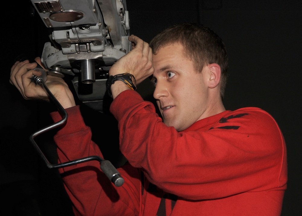 Petty Officer 3rd Class Mathew Carrell inspects an F/A-18 Super Hornet aircraft.