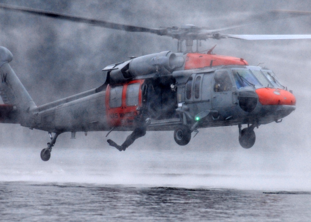 A U.S. Navy search and rescue aircrewman hoists into an MH-60S Seahawk helicopter.