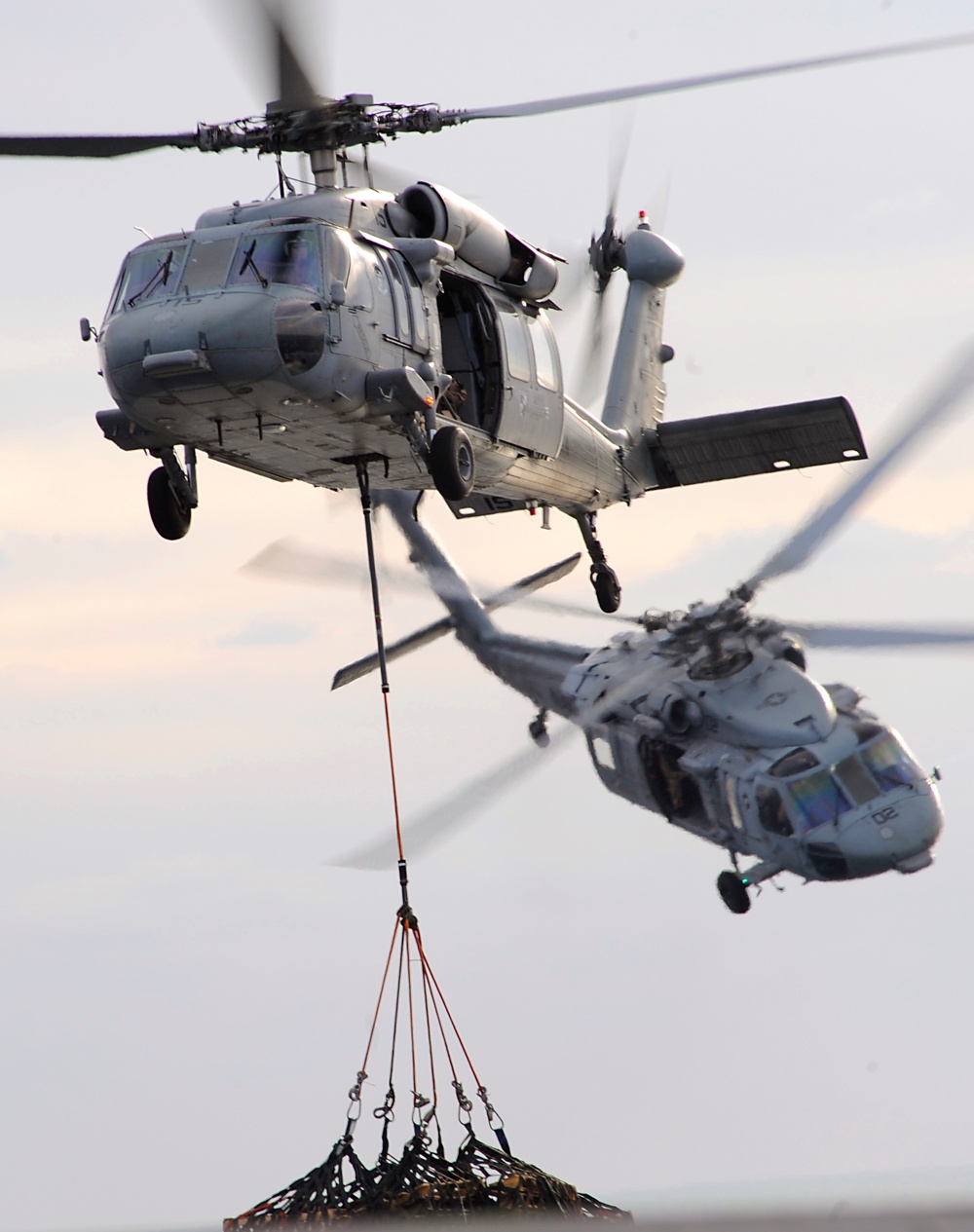 An SH-60 Seahawk helicopter deposits cargo onto the flight deck.