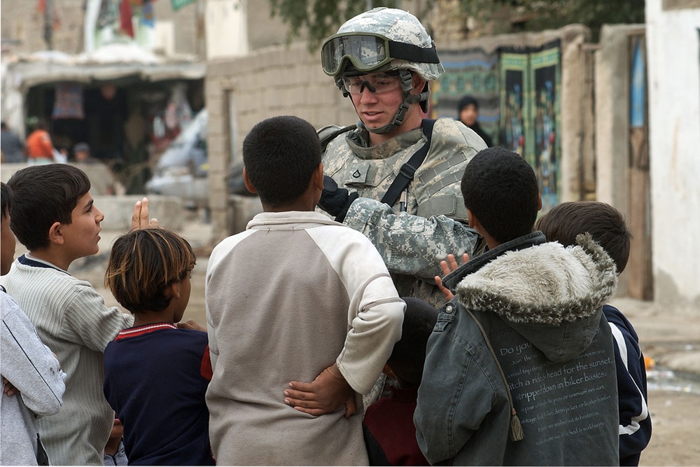 A U.S. Army soldier is surrounded by children.