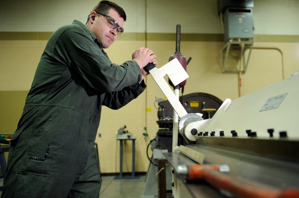 Staff Sgt. Mason Johnson uses a cornice brake to bend a seal retainer.