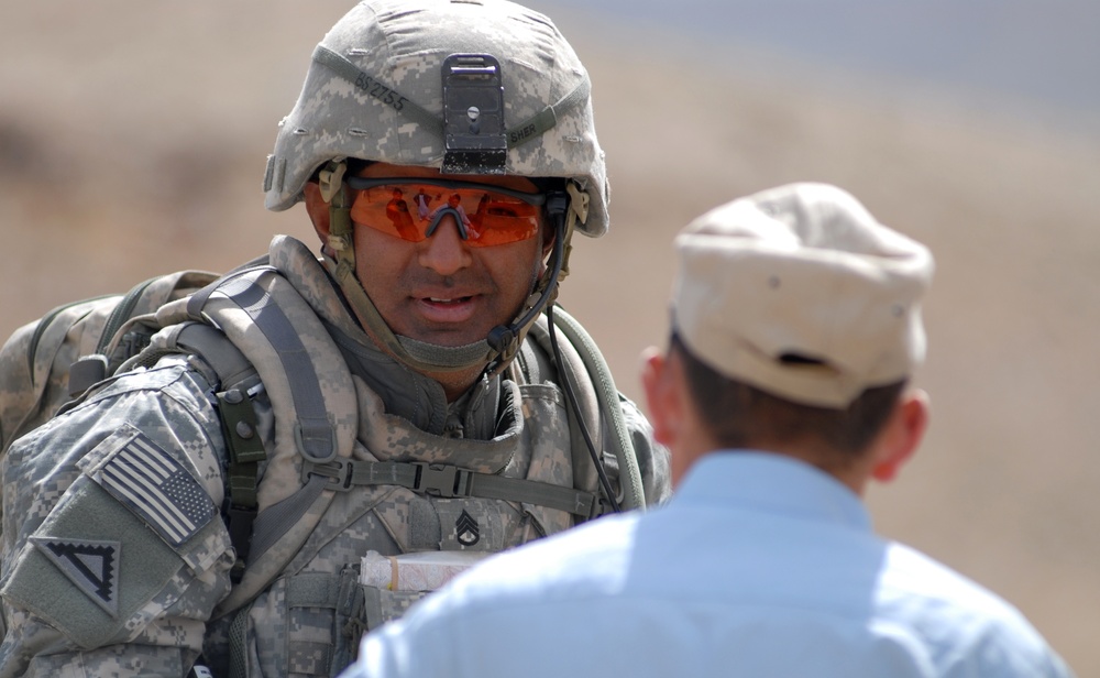 Staff Sgt. Azhar Sher speaks with an Afghan National Police officer.