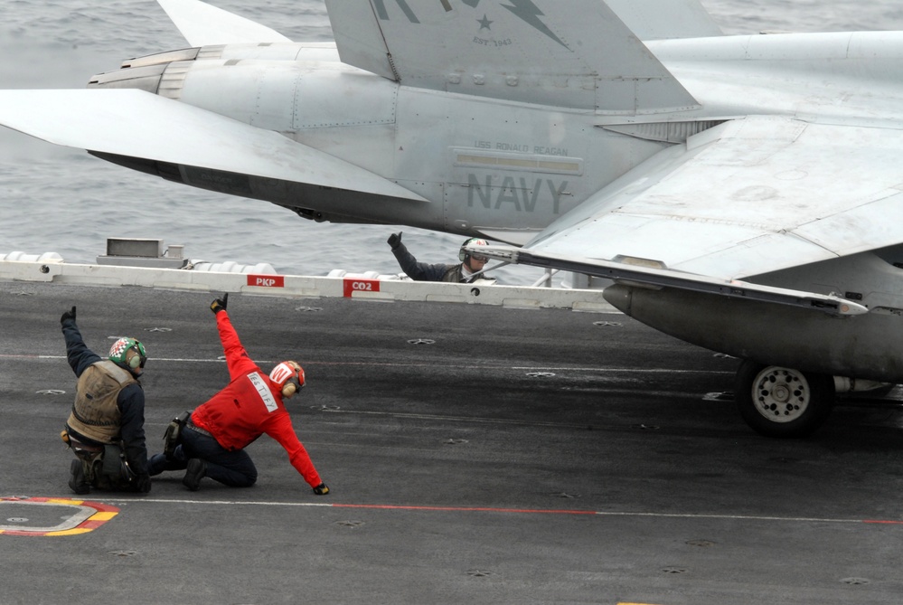Petty Officer 3rd Class Jacob New kneels behind Petty Officer 3rd Class Zachariah Tersteege as he performs final checks.