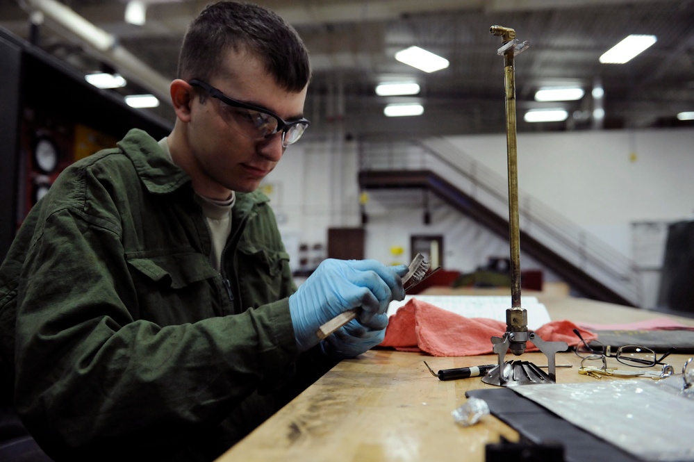 Airman 1st Class Robert Milburn uses a bristle brush to clean electrodes.