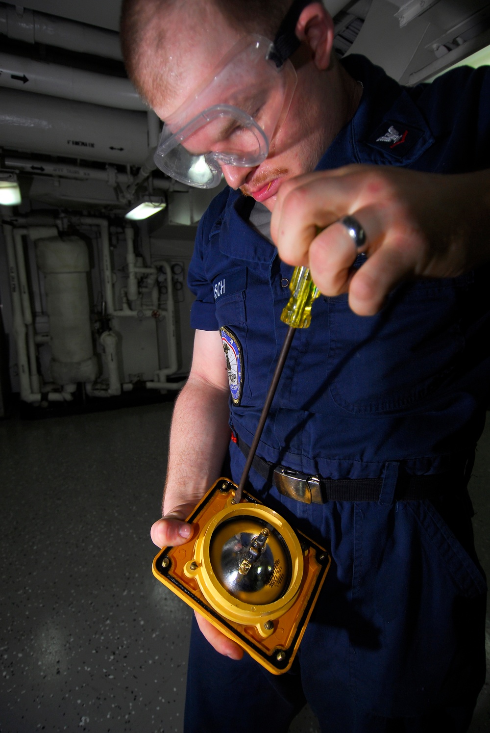 Navy Petty Officer 3rd Class Robert Paasch repairs a battle lantern.