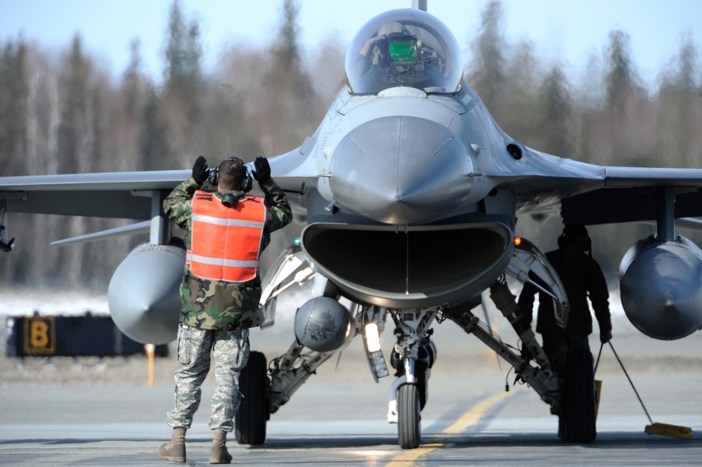 Staff Sgt. Jason Lewey marshals an F-16 Fighting Falcon.