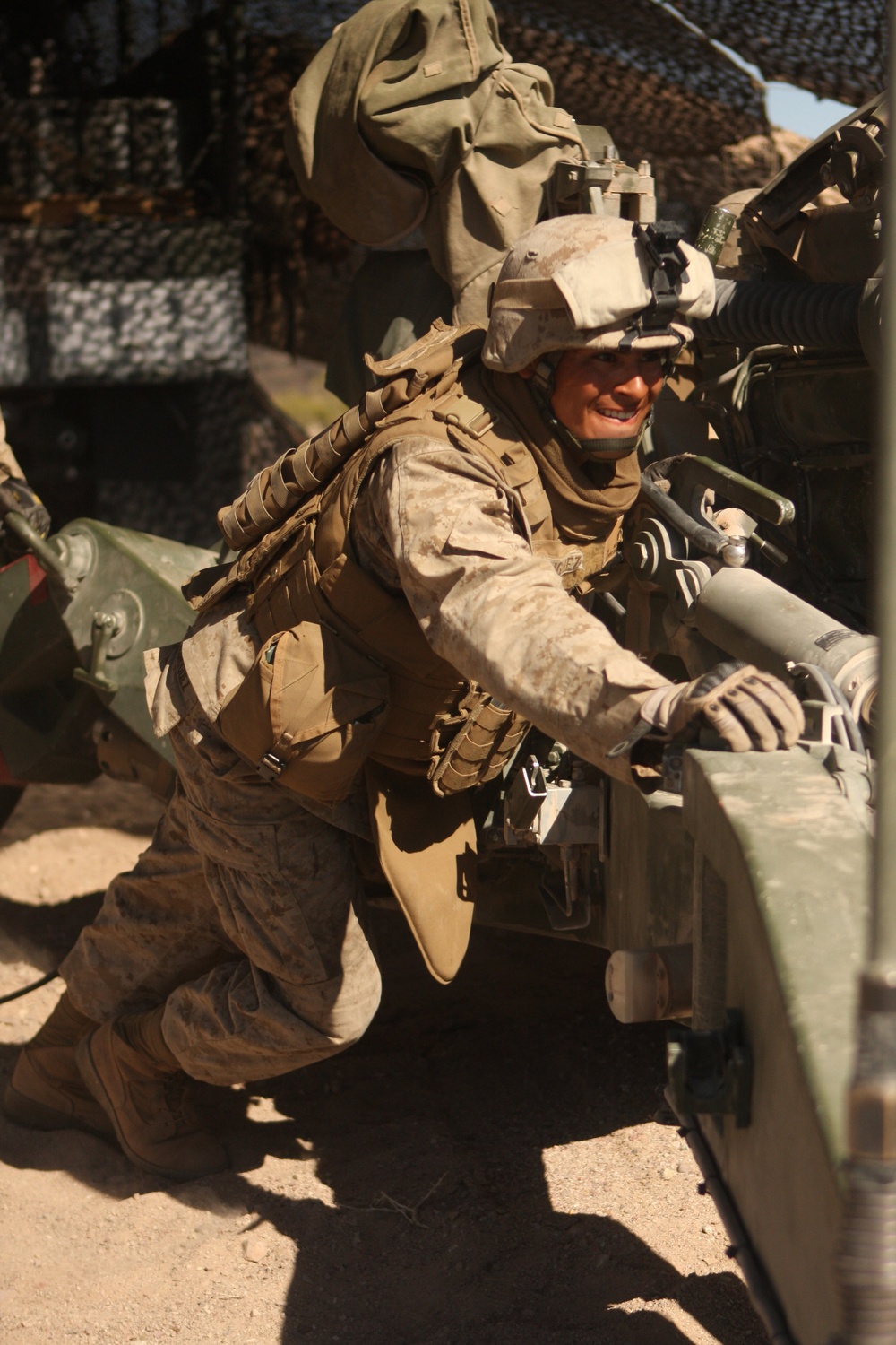Cpl. Christopher M. Rodriguez helps push an M-777A1 field howitzer.