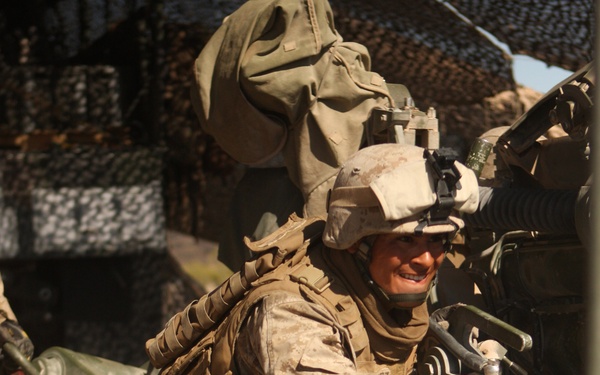 Cpl. Christopher M. Rodriguez helps push an M-777A1 field howitzer.