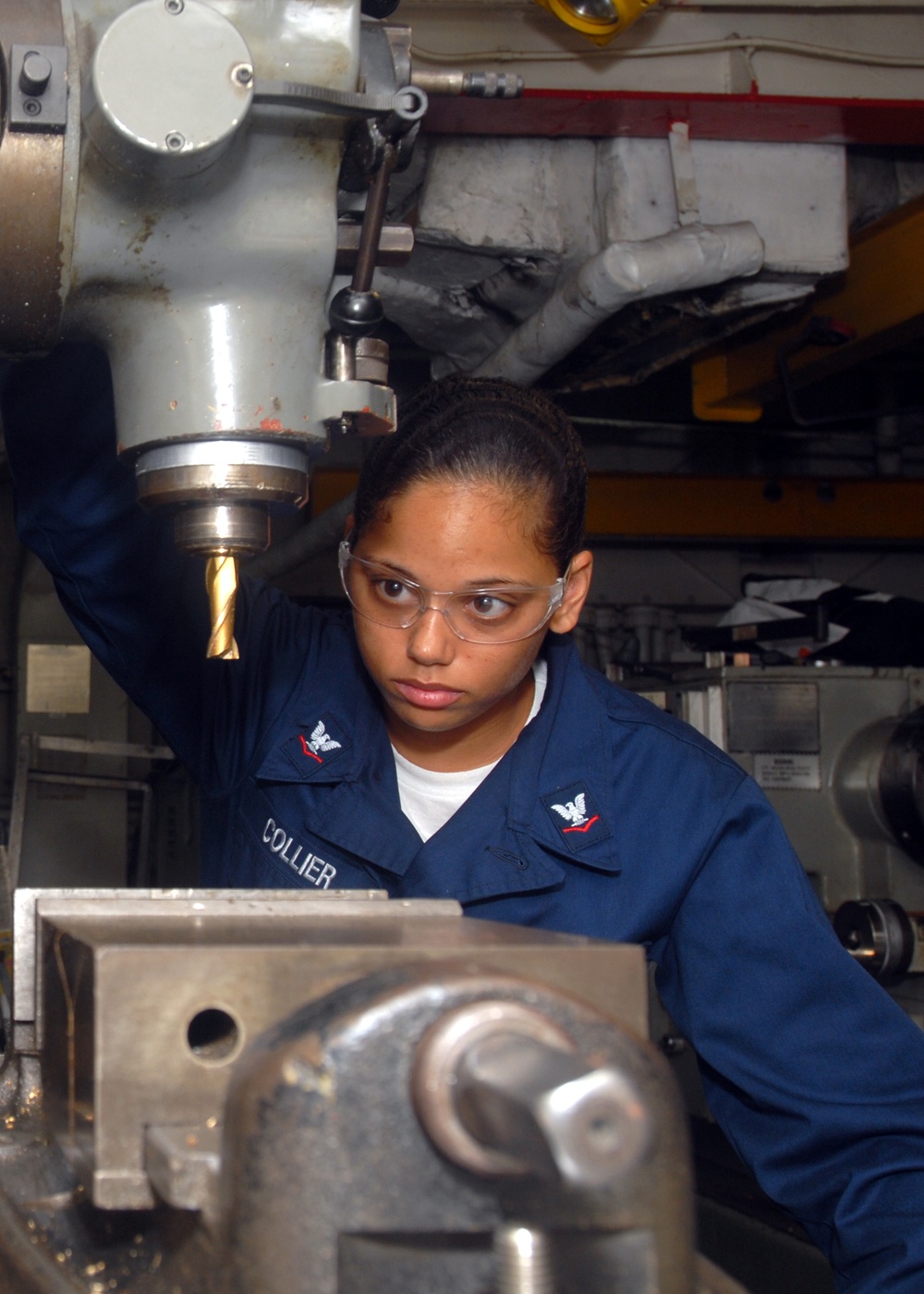 Petty Officer 3rd Class Valerie Collier performs maintenance on a milling machine.