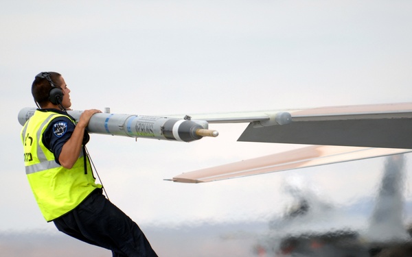A crew chief jumps up to check the top surfaces of an F-16C Fighting Falcon.