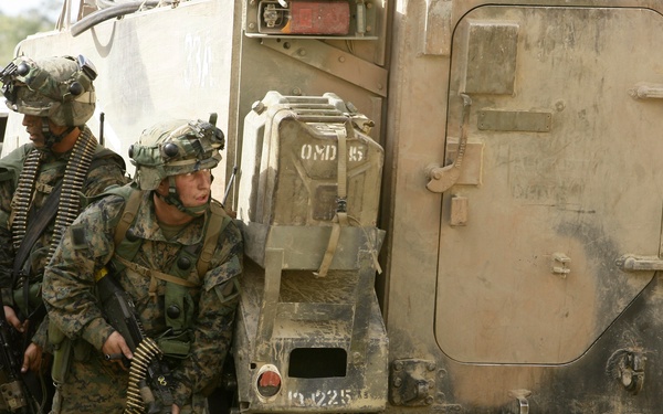 U.S. Marines take cover behind a M113 medium reconnaissance vehicle.