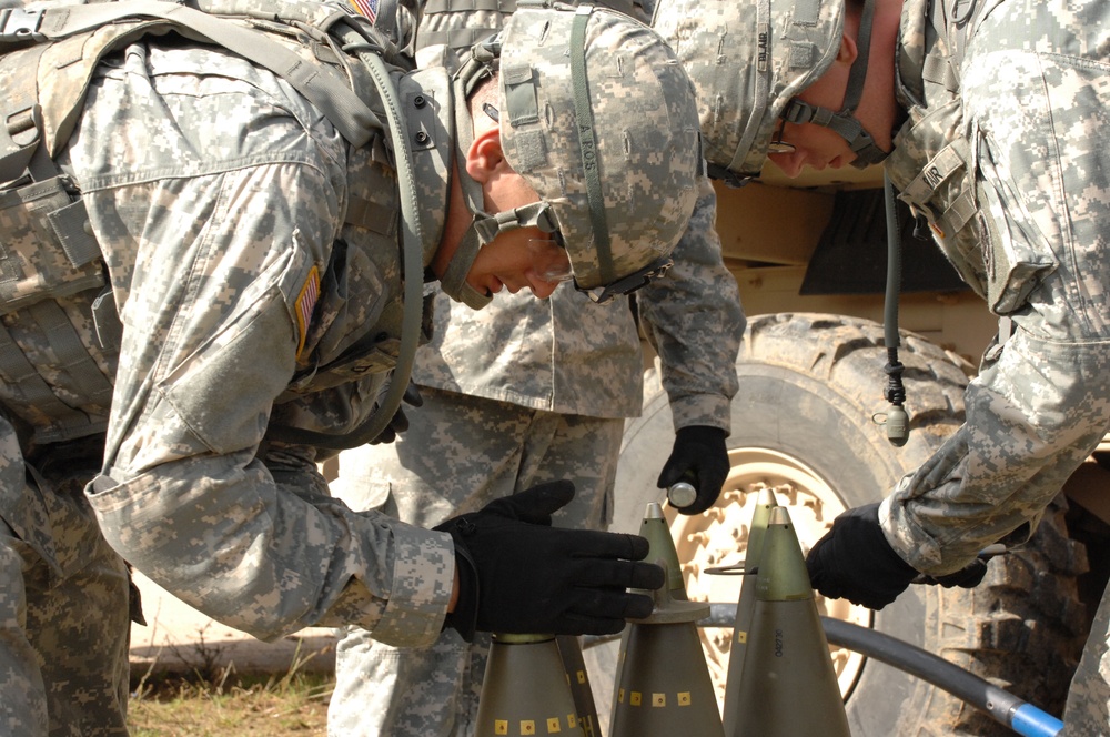 U.S. Army soldiers place fuses on artillery shells.