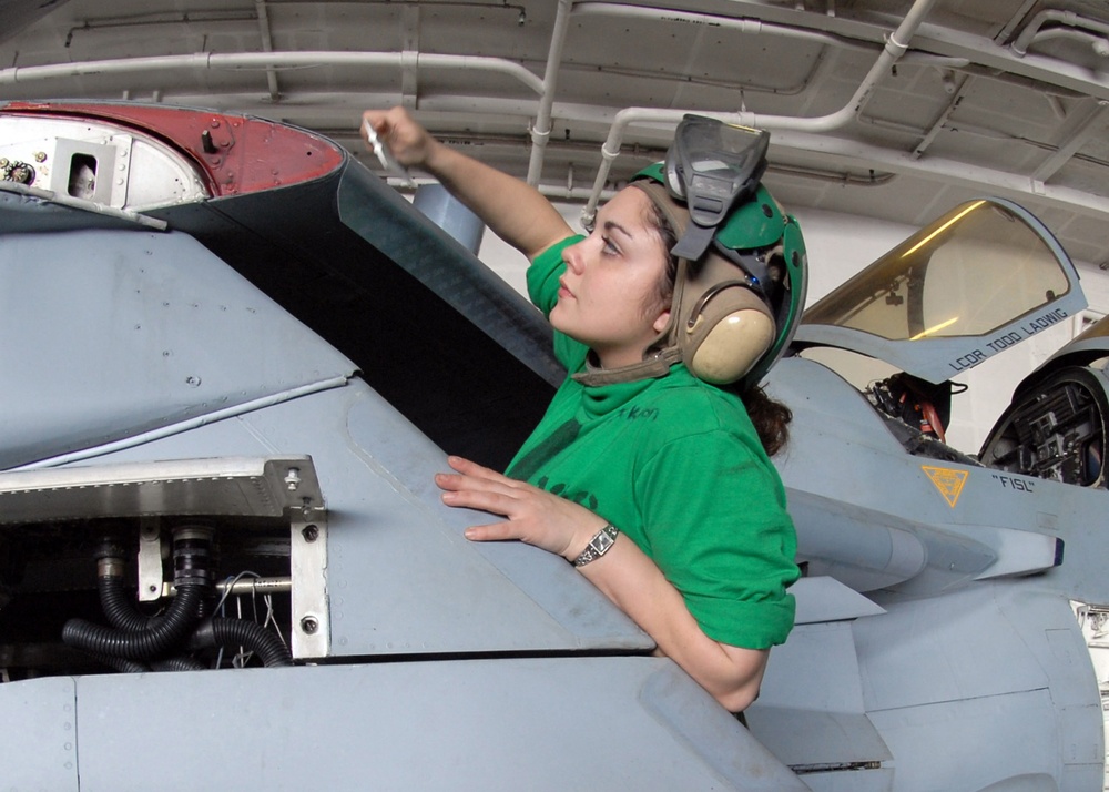 Airman Mary Jackson applies leading edge tape to the wings of an E/A-6B Prowler aircraft.
