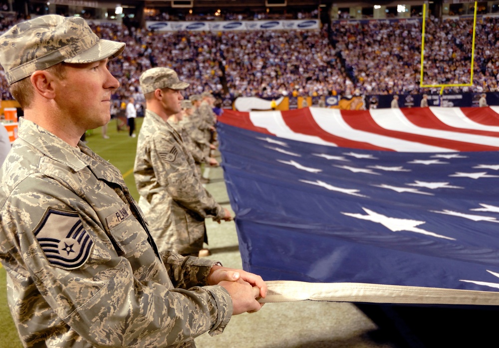 U.S. Air Force airmen hold a large U.S. flag during a Military Appreciation Game.