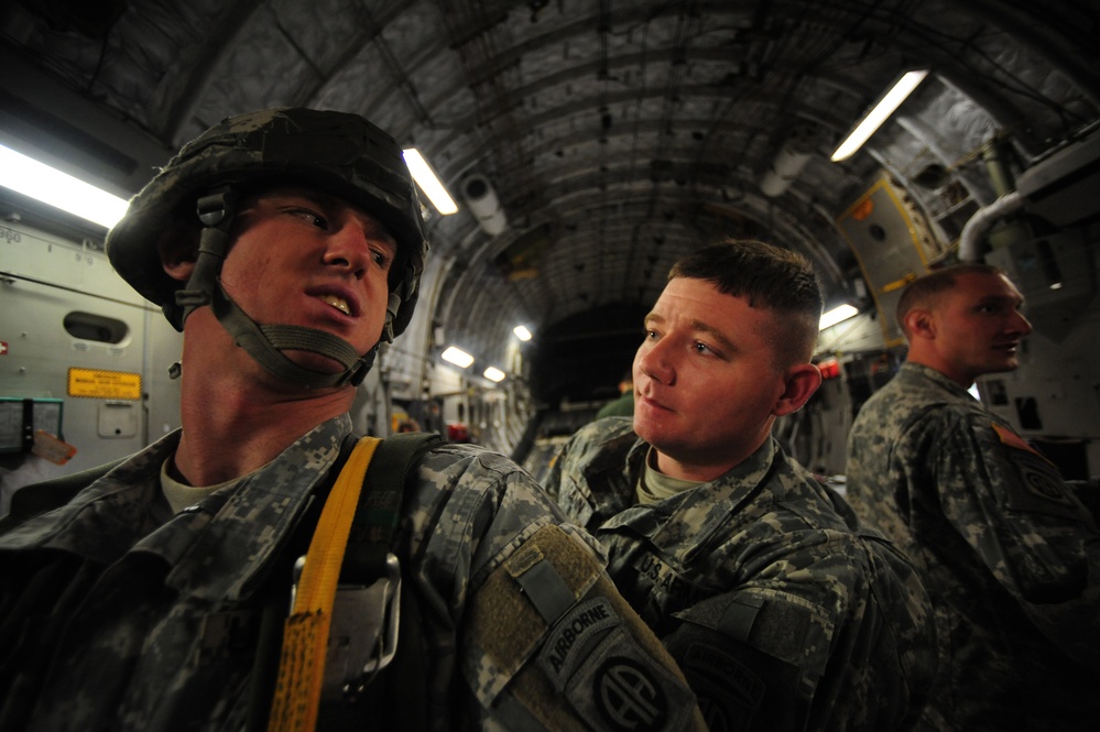 Sgt. Anthony Gann inspects Sgt. Thomas Hutton's parachute aboard a C-17 Globemaster III aircraft.
