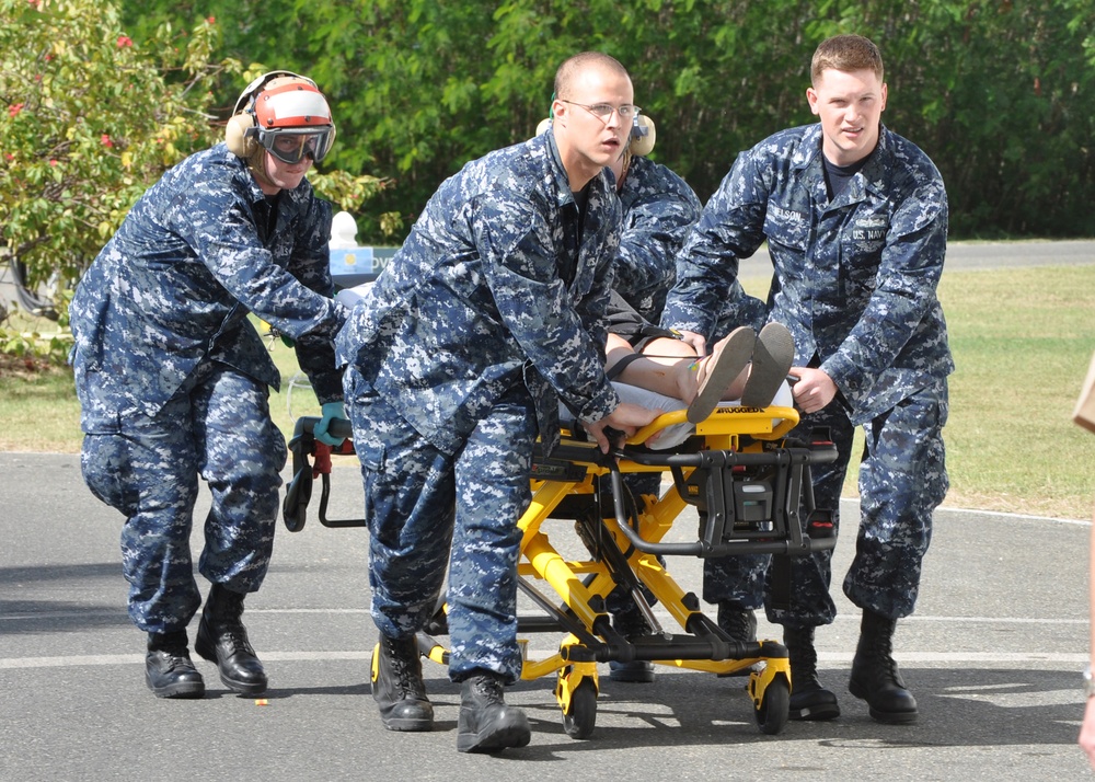 U.S. Navy sailors transport an injured U.S. citizen from a Coast Guard helicopter.