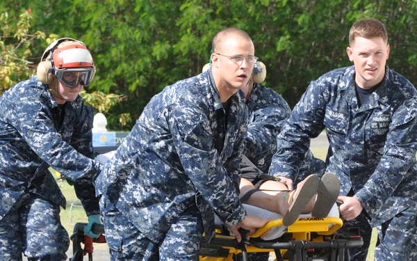 U.S. Navy sailors transport an injured U.S. citizen from a Coast Guard helicopter.