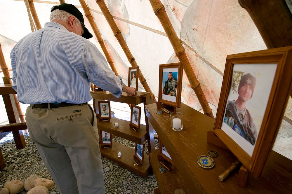 Secretary Gates places his coin at each of the photo memorials inside the Stryker Tepee Memorial.
