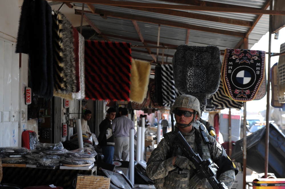 A U.S. Army soldier passes shops during an Operation Broadway Cruiser patrol.