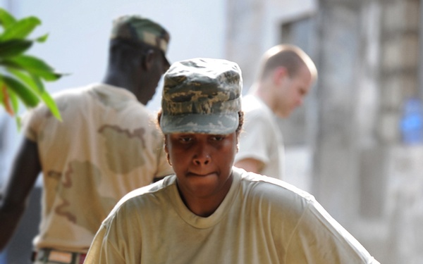 Senior Airman Shamika Moore carries a cement building block at a work site.