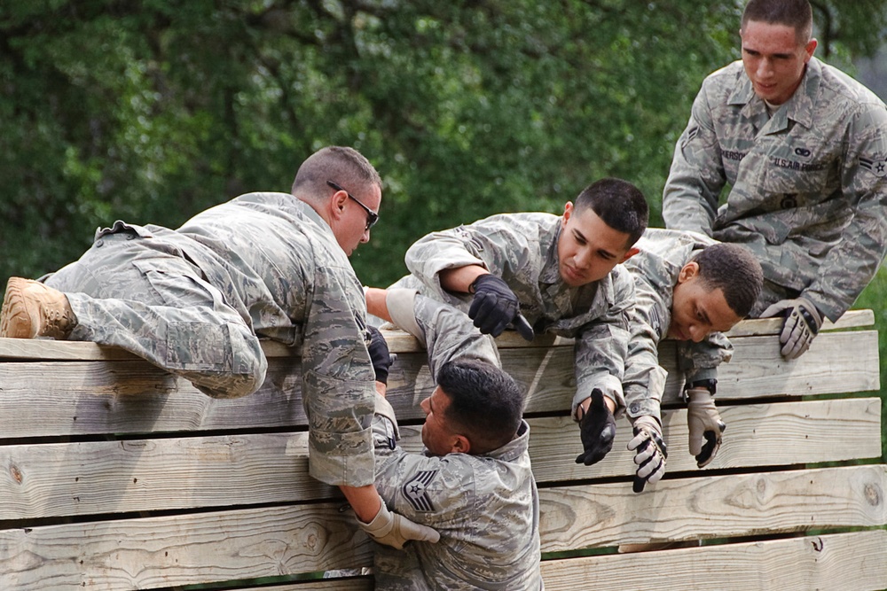 Staff Sgt. Luis Lopez gets assistance over a high wall from teammates.