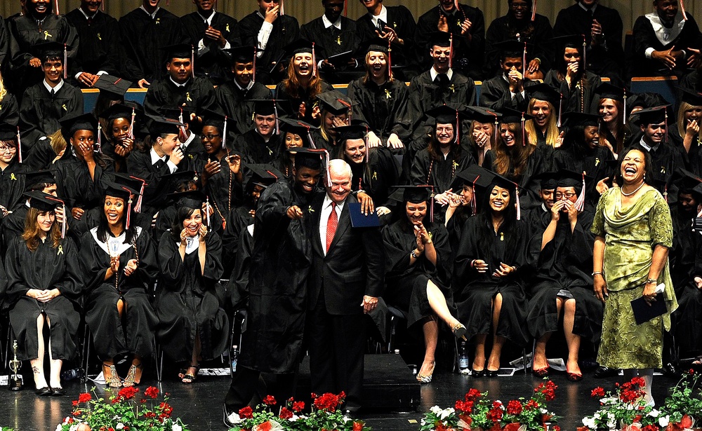 Graduates look on as Secretary Gates receives a hug.