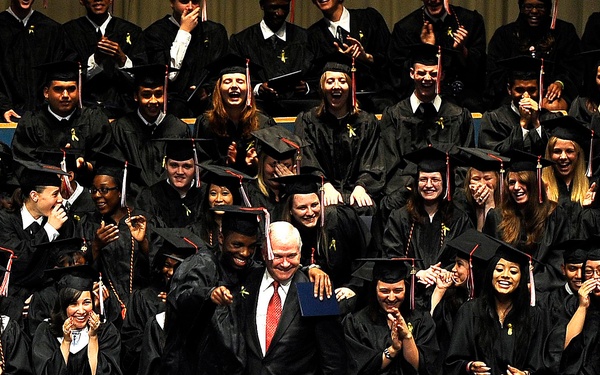 Graduates look on as Secretary Gates receives a hug.