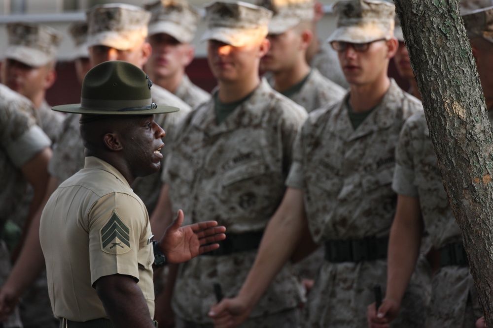 U.S. Marine Corps recruits stand at parade rest while Sgt. Harold Shade talks.