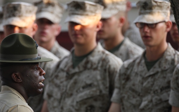 U.S. Marine Corps recruits stand at parade rest while Sgt. Harold Shade talks.