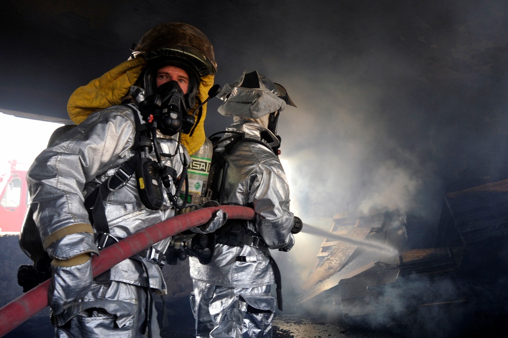 Firefighters extinguish a fire in a training room during live-burn training.