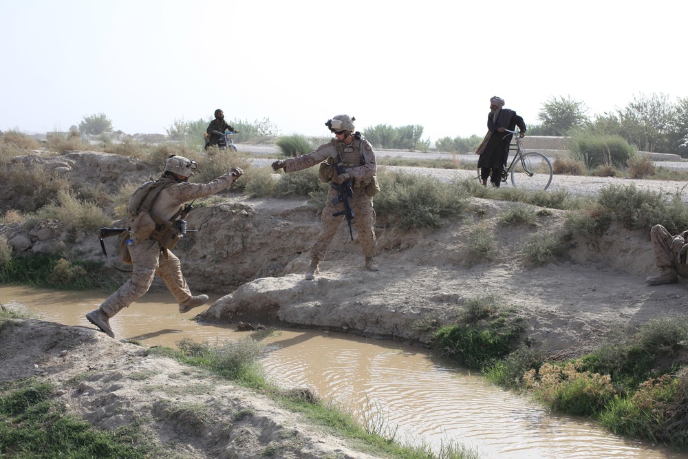 U.S. Marines jump across a canal during a patrol outside Forward Operation Base Delhi.