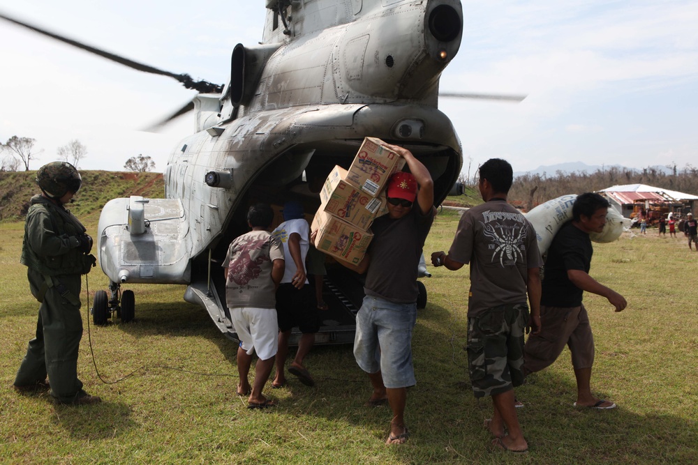 Victims of Super Typhoon Megi unload humanitarian aid supplies from a U.S. Marine Corps CH-46 Sea Knight helicopter.