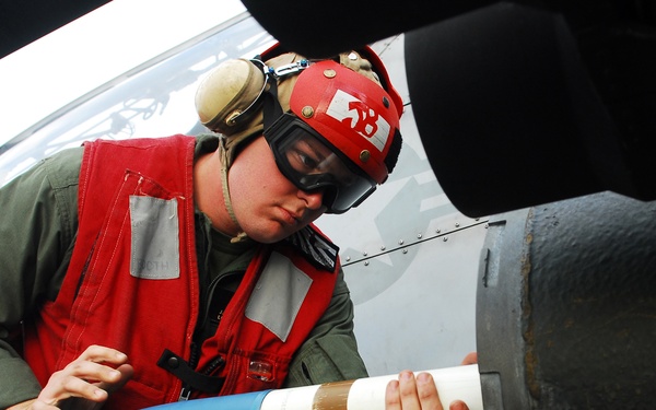 Lance Cpl. Jeremy Booth loads a 2.75-inch rocket onto an AH-1W Super Cobra helicopter.