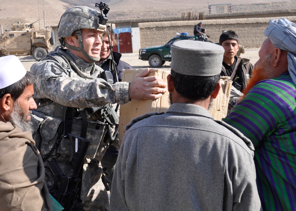 Lt. j.g. Daniel Rhame gives a box of radios to a teacher at a girl's school.