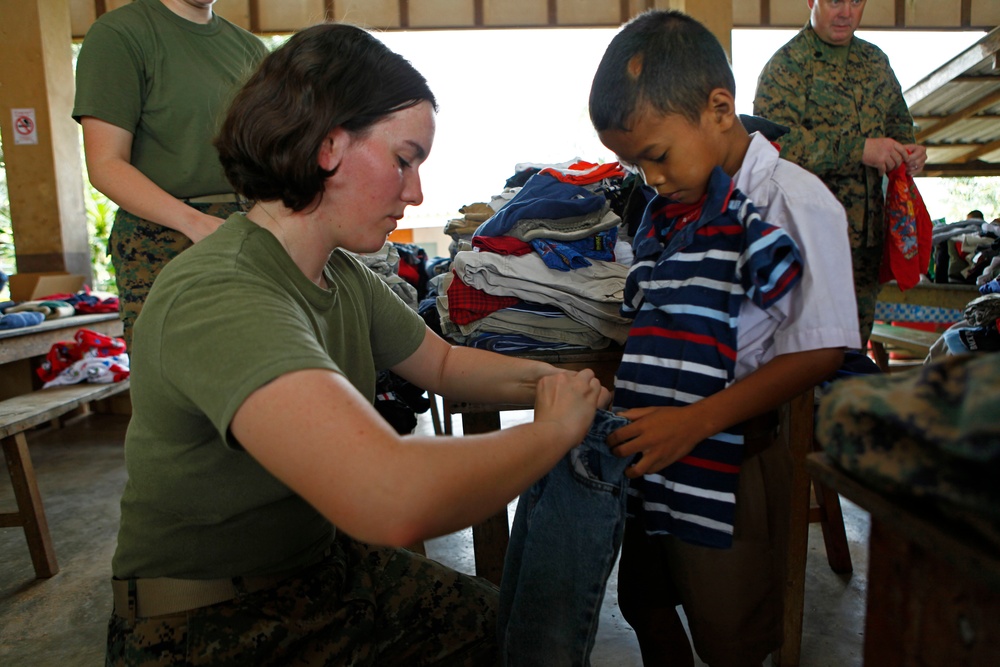 Lance Cpl. Erica R. Steele fits a student with donated clothes.