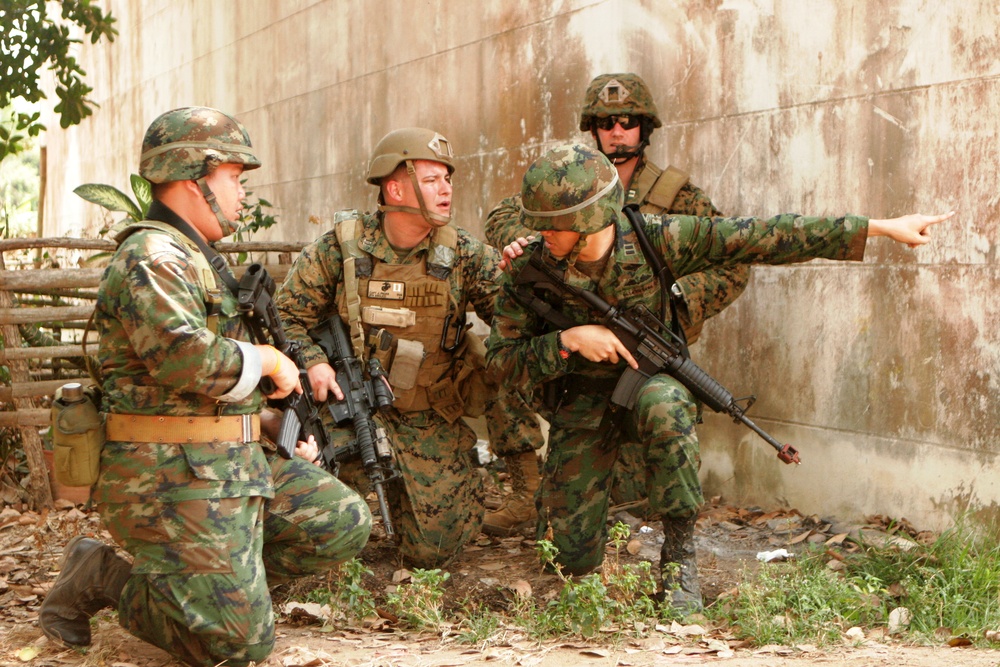 Royal Thai and U.S. Marines discuss how to eliminate hostile forces firing on them from a building.
