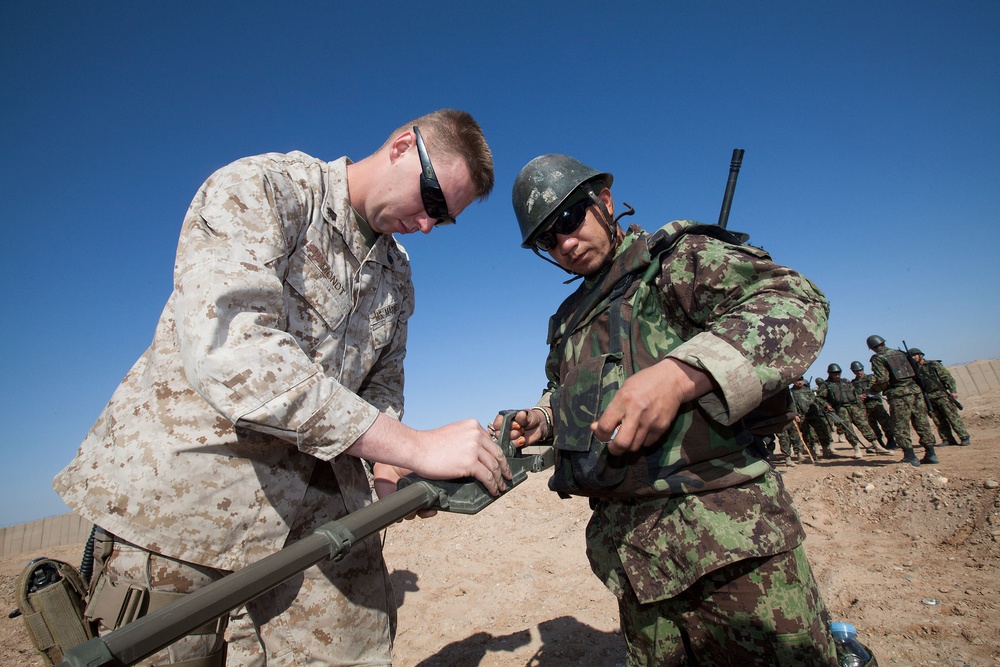 Sgt. Michael Mondt helps an Afghan National Army soldier adjust a combat metal detector.